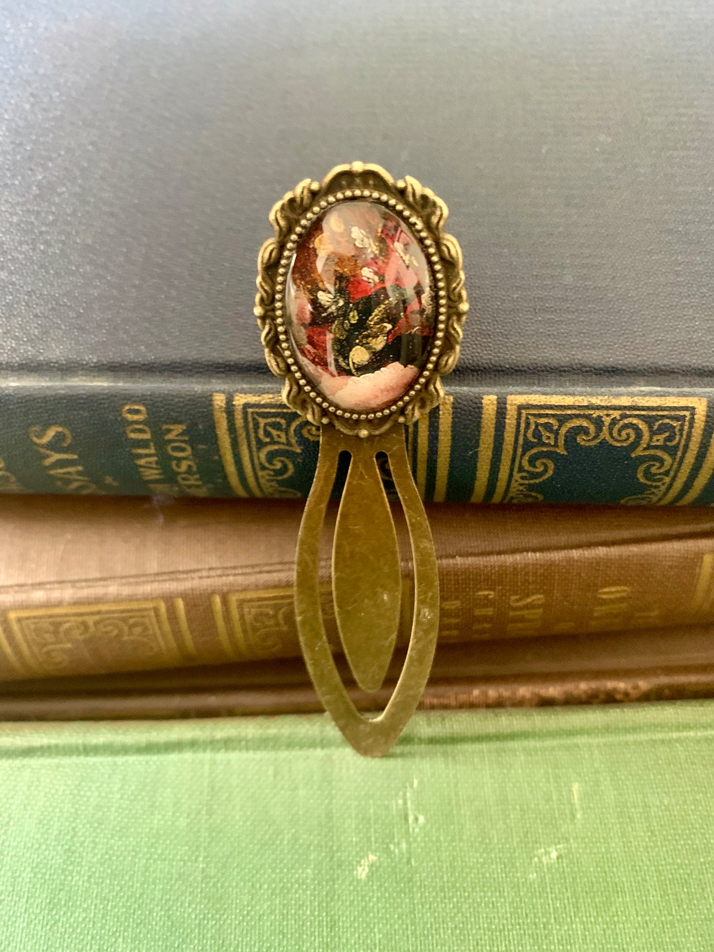 Decorative antique-style bookmark with a central floral design art print on top of vintage books.