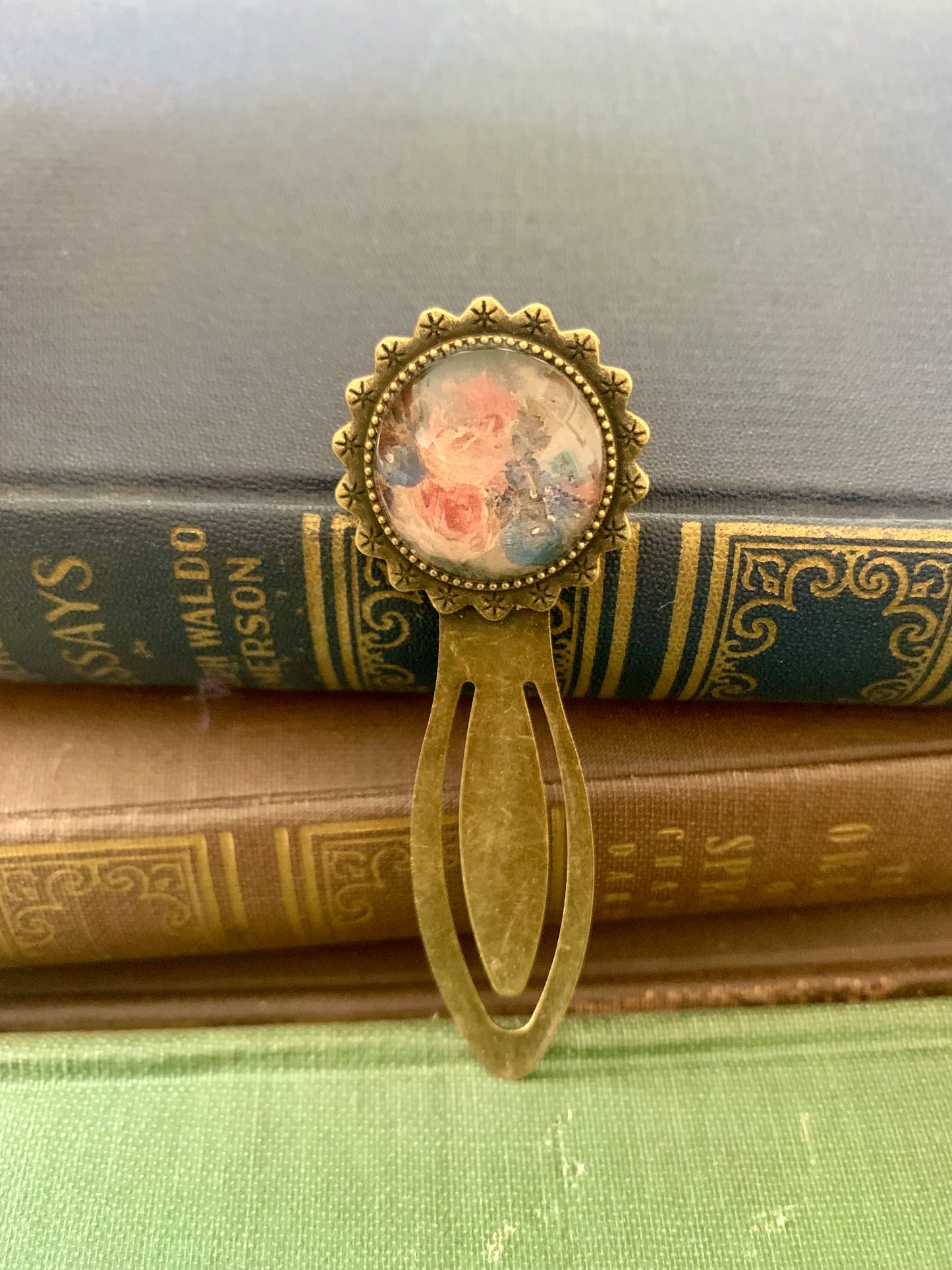 Decorative antique-style bookmark with a central floral design art print on top of vintage books.