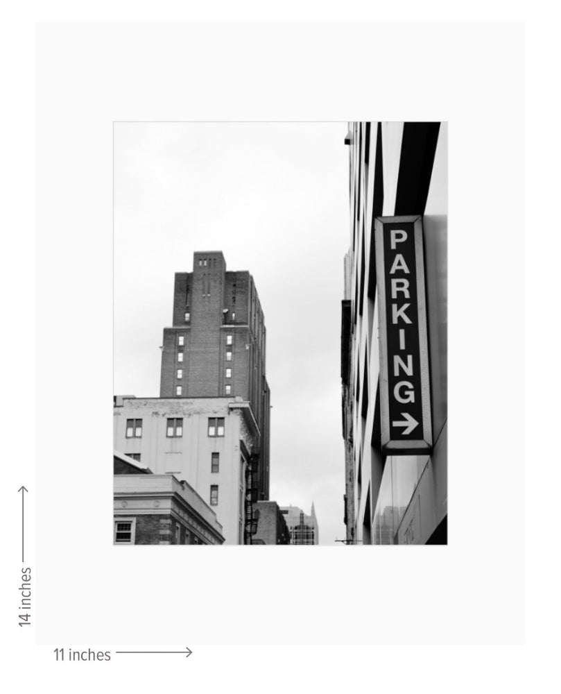 Black and white photo of a cityscape with a parking sign, dimensions indicated.