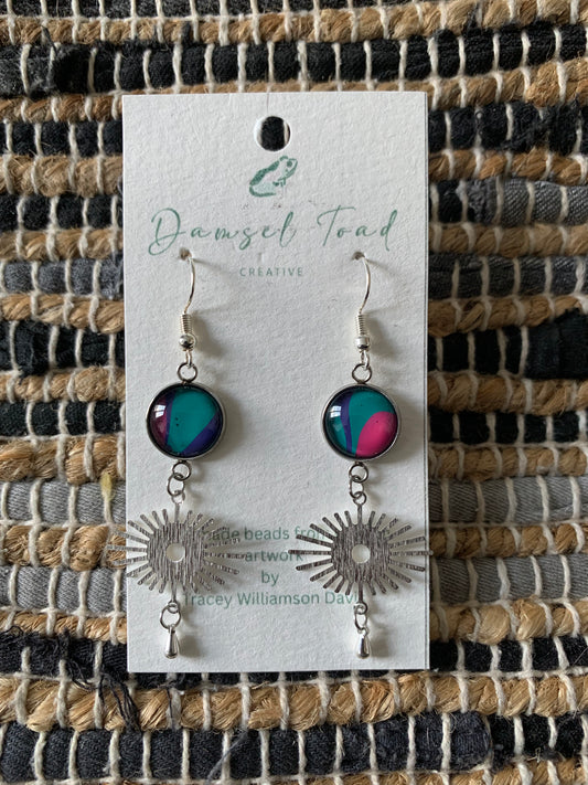Earrings on a 'Damsel Toad Creative' card against a woven fabric background
