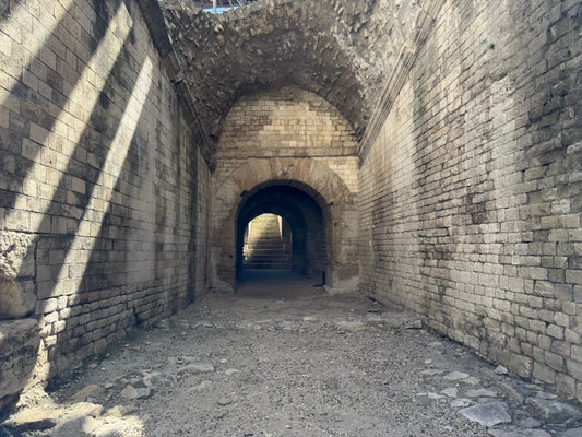 Tunnel with stone walls and a gravel floor, showing signs of wear.